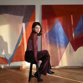 Self-portrait in front of two of my artworks. On the left: "broken femur", on the right: "healed femur", 2025